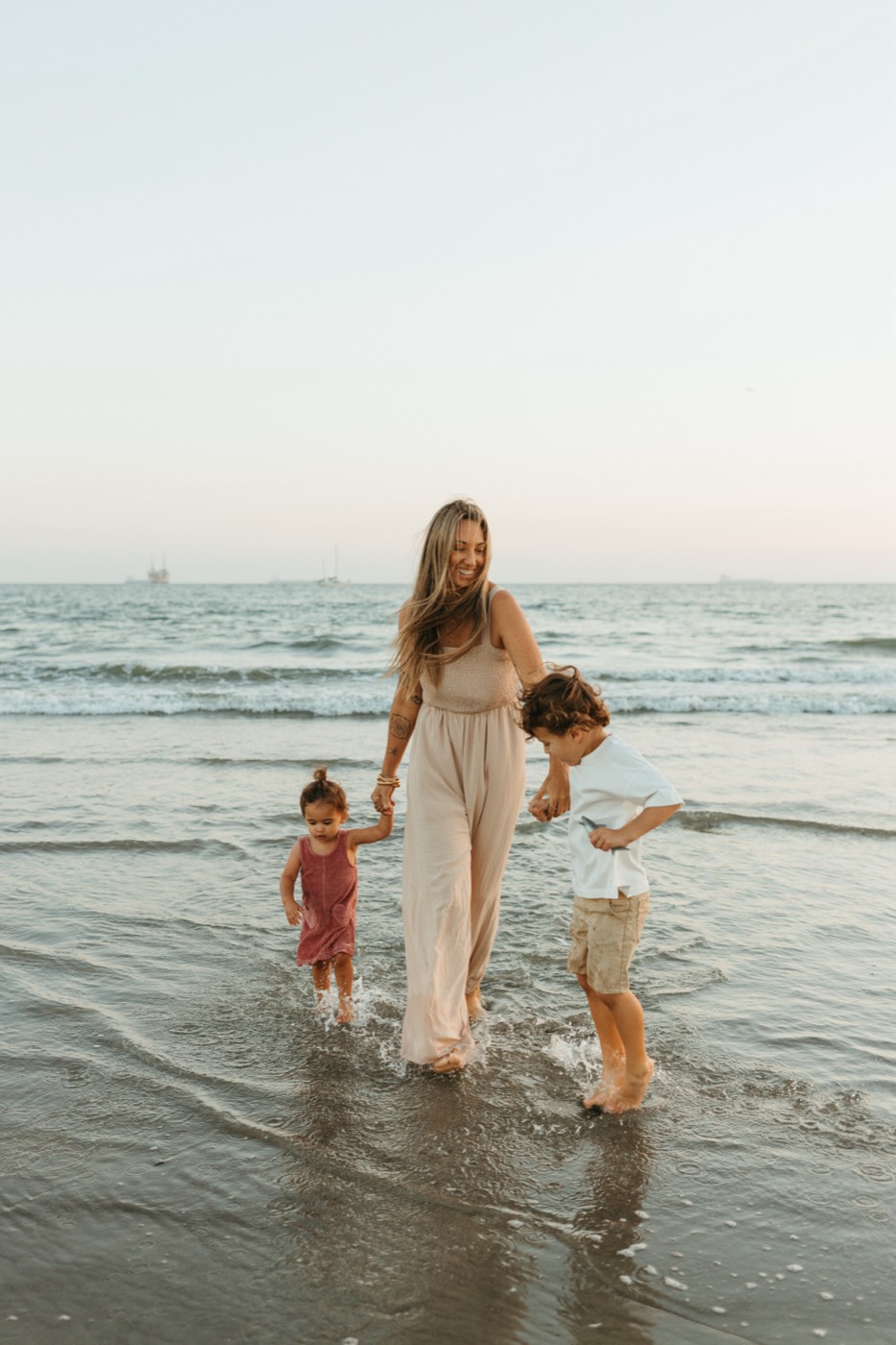 Crystal Ortiz holding hands with her two kids in the waves at a Long Beach beach